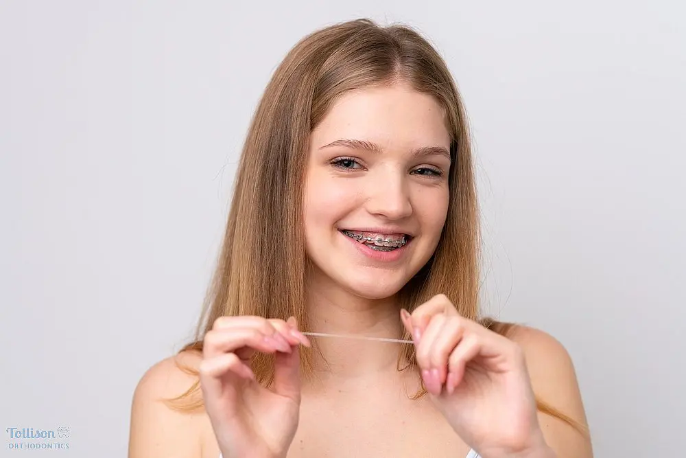 teenager russian girl with metal braces and floss isolated white background - How to Floss with Braces in Greenville, SC.