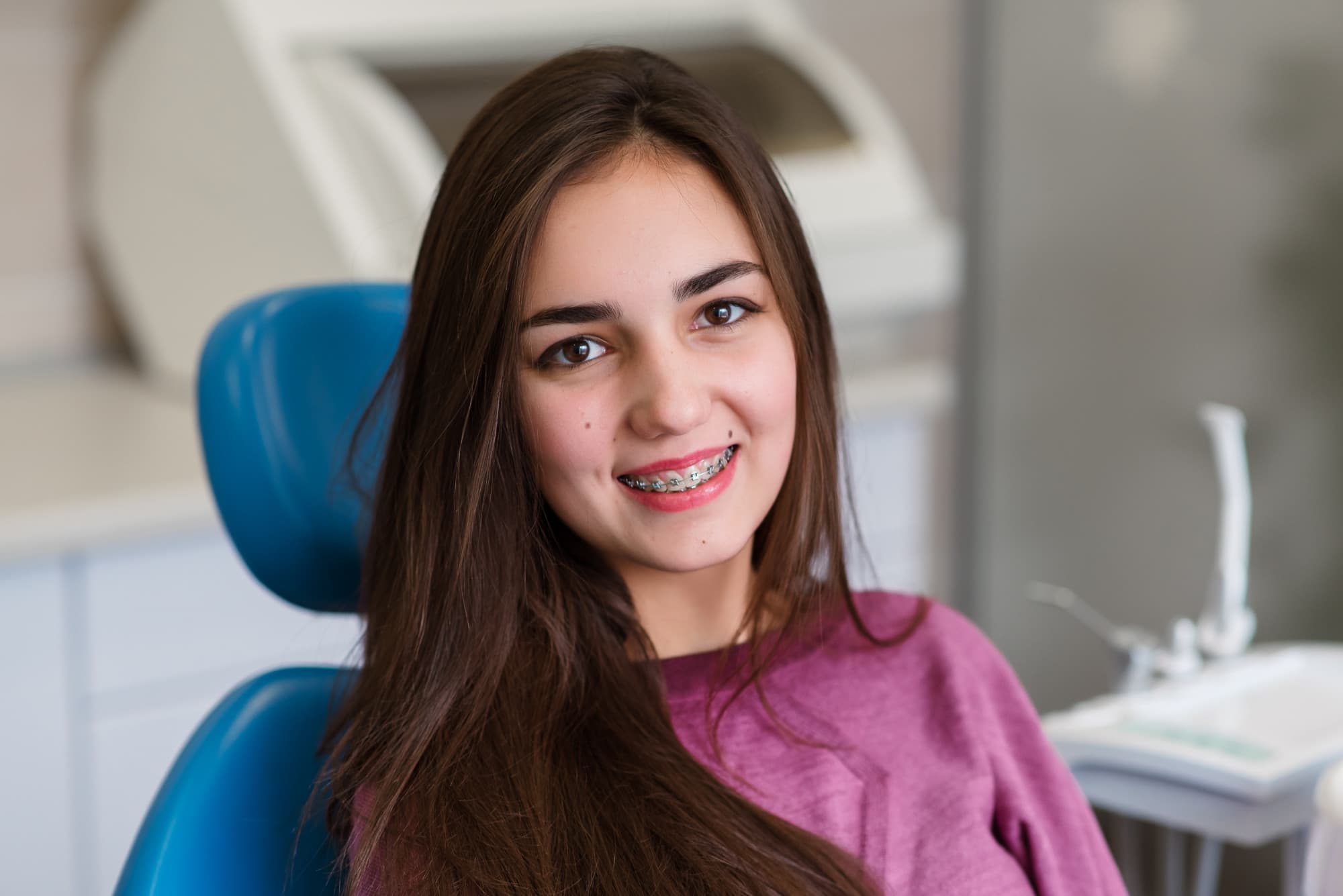 A woman with long hair revealing metal braces on their teeth at Tollison Orthodontics in Greenville, SC
