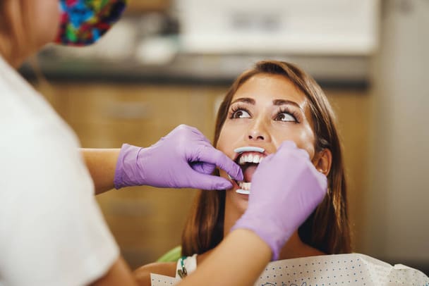 A woman close-up reveals highlighting of lingual braces discreetly aligned on the lower teeth at Tollison Orthodontics in Greenville, SC
